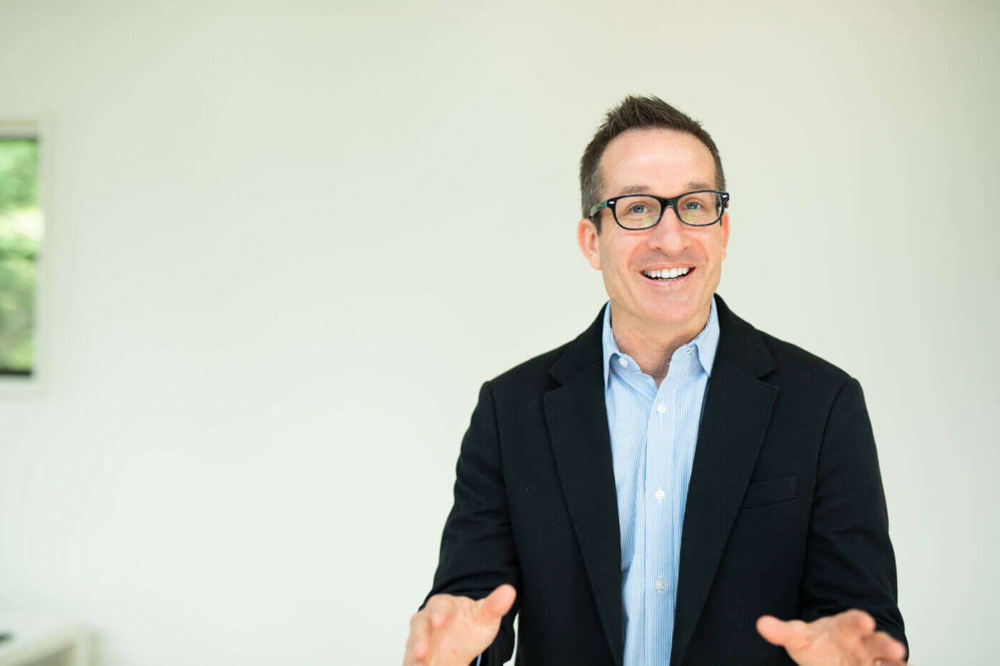 Feature image Picture of a professional facilitator, standing confidently and engagingly. He is wearing business attire and exemplifies expertise and leadership in guiding productive conversations.