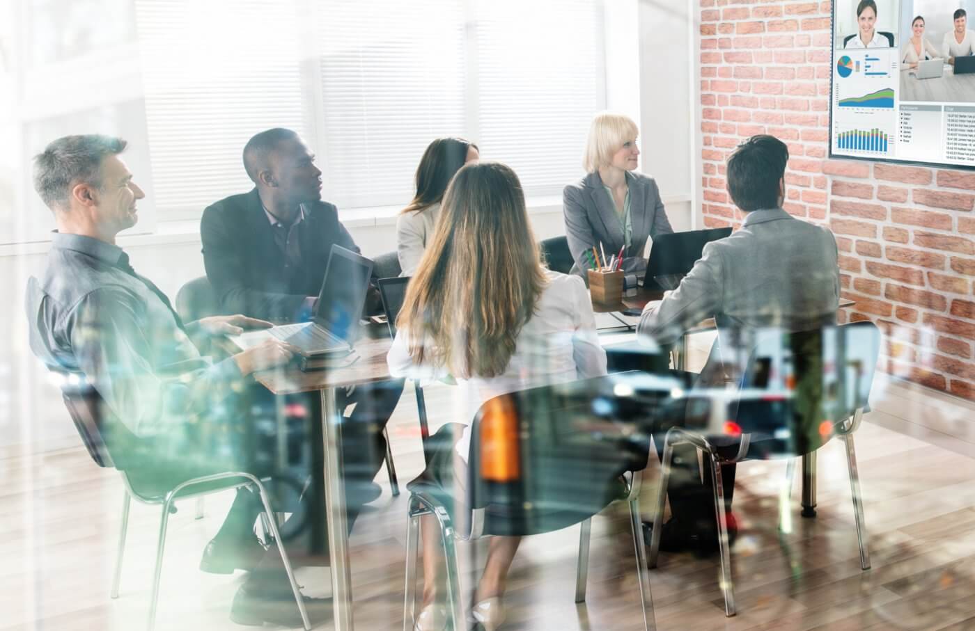 employees sitting at table looking at tv for group training